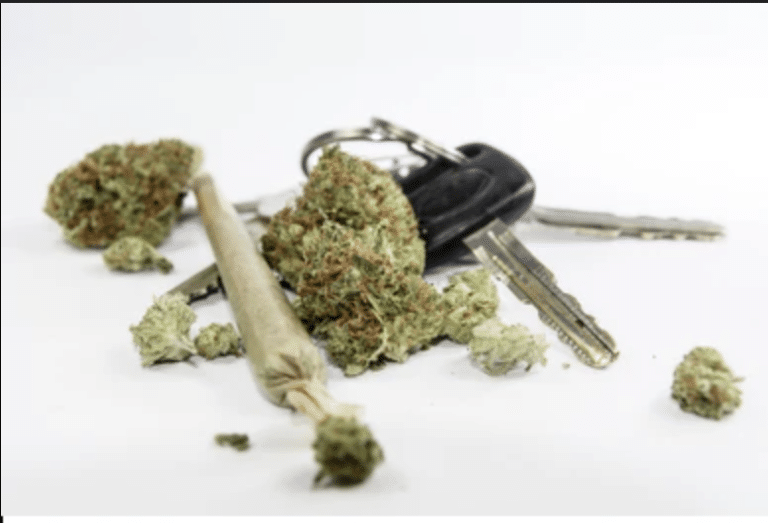 Cannabis buds and a rolled joint next to car keys, illustrating the dangers of driving under the influence of marijuana